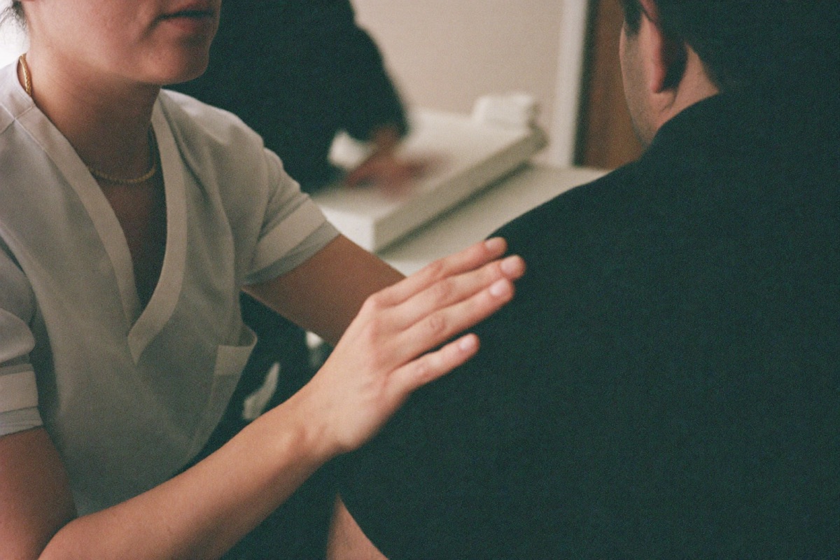 Nurse placing a reassuring hand on a patient’s shoulder